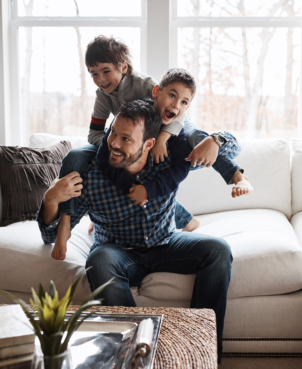 father playing with sons on the couch