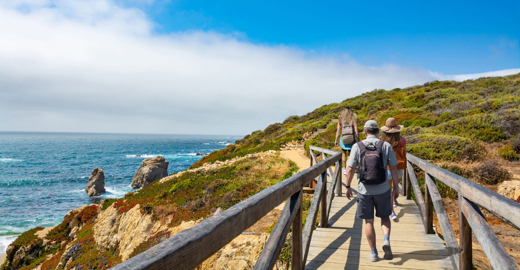 Three people hike a coastal trail in Northern California