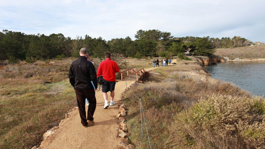 People hike by the pond at Point Lobos State Natural Reserve in Carmel-by-the-Sea, CA